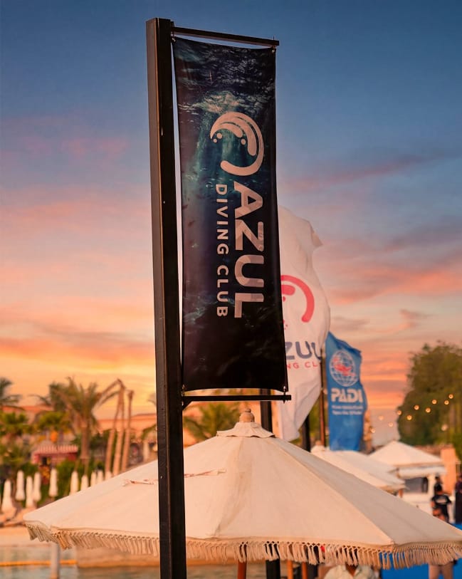 The Azul Diving Club banner at sunset on the beach, flying beside a PADI flag